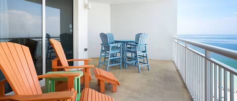 Ein Balkon mit Blick auf den Ozean, ausgestattet mit Gartenmöbeln inklusive Stühle und Tische.