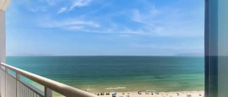 A balcony with a view of a beach and ocean.