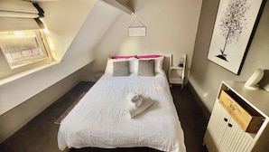 A bedroom with a bed, a window, a radiator, and a framed picture on the wall. - Gracious Apartment in Historic Sheffield Georgian Quarter (Sheffield City Centre)