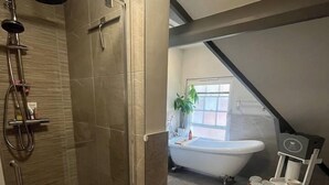 A modern bathroom with a glass-enclosed shower, a freestanding bathtub, and a small shelf with toiletries. - Gracious Apartment in Historic Sheffield Georgian Quarter (Sheffield City Centre)