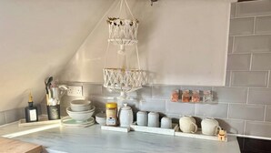 Une cuisine dotée d’un plan de travail en marbre, d’un luminaire suspendu en macramé et d’un crédence carrelée.
