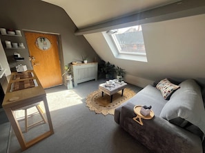 A compact living space with a loft bedroom, a dining area, and a seating area with a sofa and a small table.