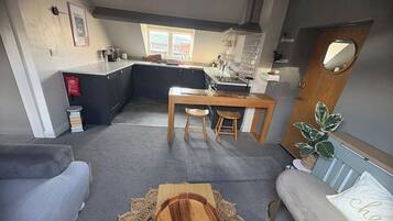 A modern kitchen with a dining area, a sofa, and a small table with a placemat.