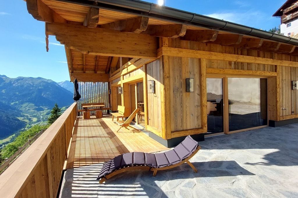 A wooden cabin with a balcony overlooking a mountainous landscape.