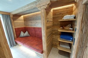 En inredning med trädetaljer, en röd soffa, trähyllor och ett fönster med gardiner.