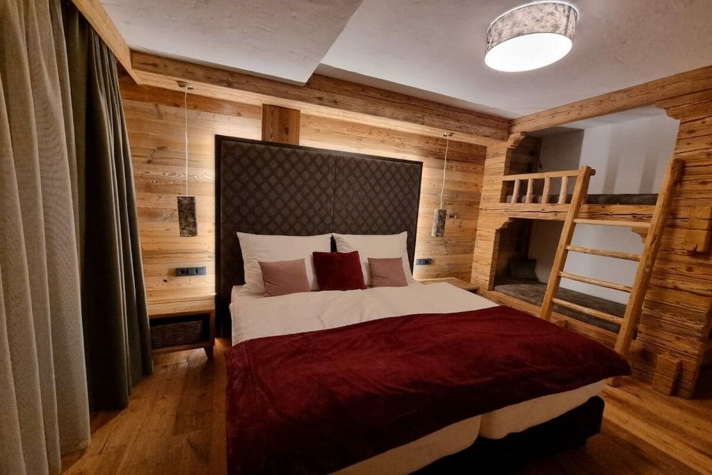 Ein Zimmer mit einem Bett, einem Etagenbett und einer Leiter.