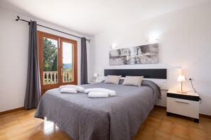Ein Schlafzimmer mit einem großen Bett, einem Nachttisch, einer Wandlampe und einem Gemälde.