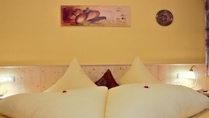 Ein Hotelzimmer mit einem Bett, Kissen, einer Wanduhr, einem Gemälde und Nachttischlampen.