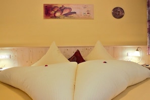 A hotel room with a bed, pillows, a wall clock, a painting, and bedside lamps. - Holiday apartment in Kappl with swimming pool (Kappl)