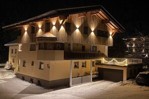 Ein mehrstöckiges Gebäude mit Balkon, Garage und verschneitem Gelände.