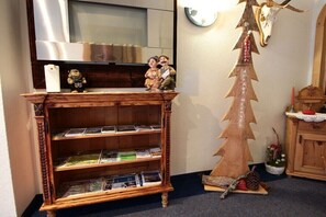 A wooden bookshelf with magazines, a decorative Christmas tree, and a mounted deer skull. - Holiday apartment in Kappl with swimming pool (Kappl)