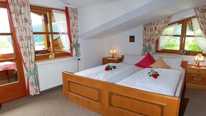 A bedroom with a wooden bed, two bedside tables with lamps, a window with curtains, and a radiator. - Apartment in Riezlern with swimming pool (Riezlern)
