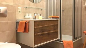 A bathroom with a glass shower enclosure, a wooden vanity with a mirror, and a toilet. - Apartment in Riezlern with swimming pool (Riezlern)