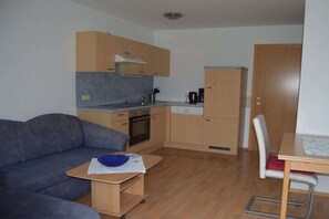 Ein gemütlicher Wohnbereich mit Küchenzeile, einer Couch, einem kleinen Tisch und einem Essbereich.