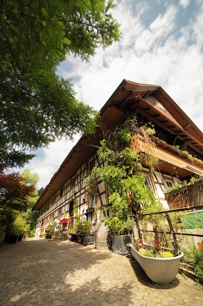 A traditional half-timbered building with a sloped roof, surrounded by potted plants and a cobblestone pathway. - Vrbo Property (Ottenhöfen im Schwarzwald)
