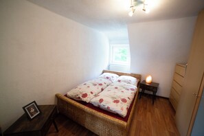Une chambre avec un lit simple, une table de chevet, une commode et une armoire.