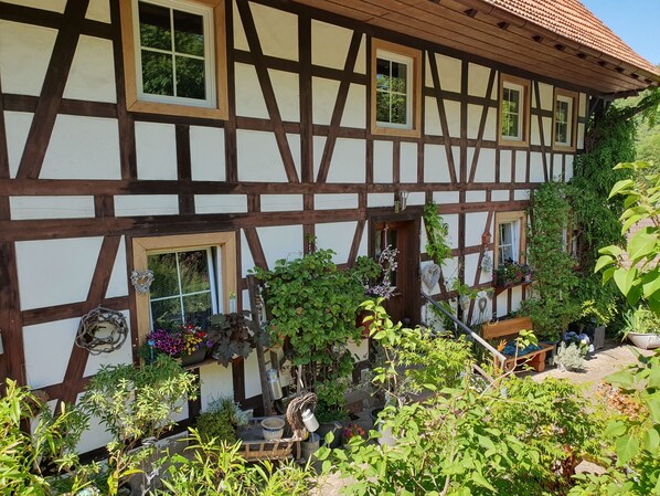A traditional half-timbered house with multiple windows and a garden area with various plants and flowers. - Vrbo Property (Ottenhöfen im Schwarzwald)