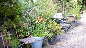 Une terrasse de jardin agrémentée de plantes en pot, d’une chaise en métal et d’une table.