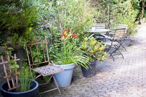 A garden patio with potted plants, a metal chair, and a table. - Vrbo Property (Ottenhöfen im Schwarzwald)