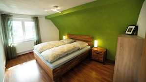 Une chambre à coucher avec un lit en bois, des tables de chevet, une petite table de nuit avec une lampe et un radiateur.