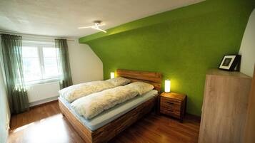 Ein Schlafzimmer mit einem Holzbett, Nachttischen, einem Beistelltisch mit Lampe und einem Heizkörper.