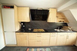 A compact kitchen with a black countertop, wooden cabinets, a built-in oven, and a small sink.