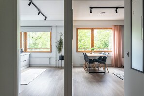 Cuina moderna amb finestra, zona de menjador amb taula i cadires, i una planta en test.