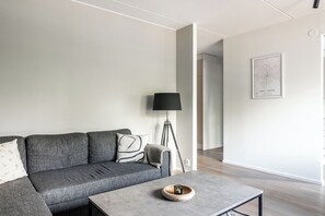 Un salón moderno con un sofá gris, una lámpara de pie y una mesa de centro con una vela.