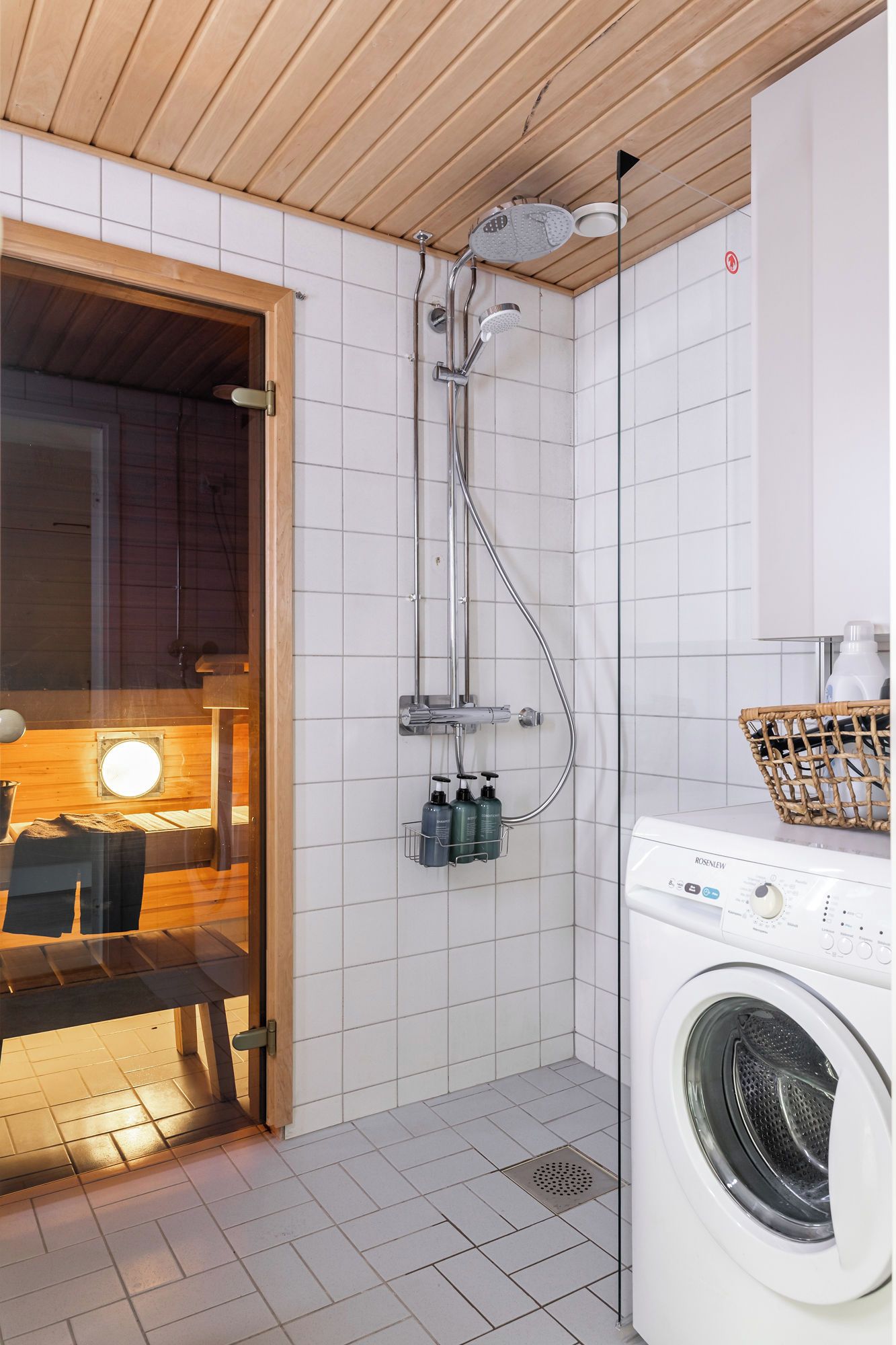 Une salle de bain moderne équipée d’une douche, d’un lave-linge et d’un banc en bois.