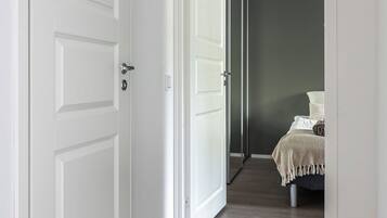 Un couloir menant à une chambre à coucher, où se trouvent un lit et une table de chevet.