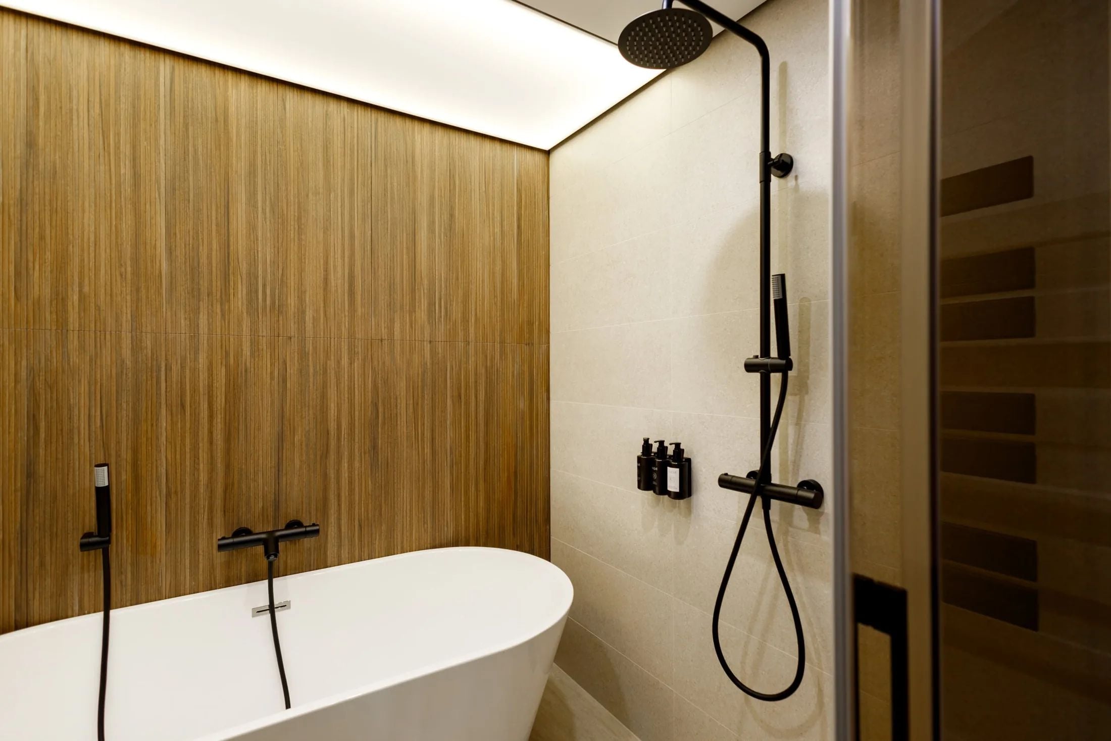 Une salle de bain moderne avec une baignoire sur pied, une douche avec un pommeau de douche amovible et un panneau de commande fixé au mur.
