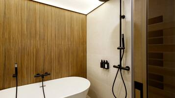 Une salle de bain moderne avec une baignoire sur pied, une douche avec un pommeau de douche amovible et un panneau de commande fixé au mur.