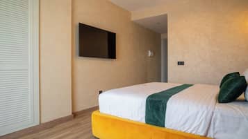 Habitación de hotel con cama, televisor montado en la pared y puerta que da a otra habitación.