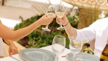 A table set with plates, glasses, and a fruit bowl, with a bottle of wine and a smartphone on it.