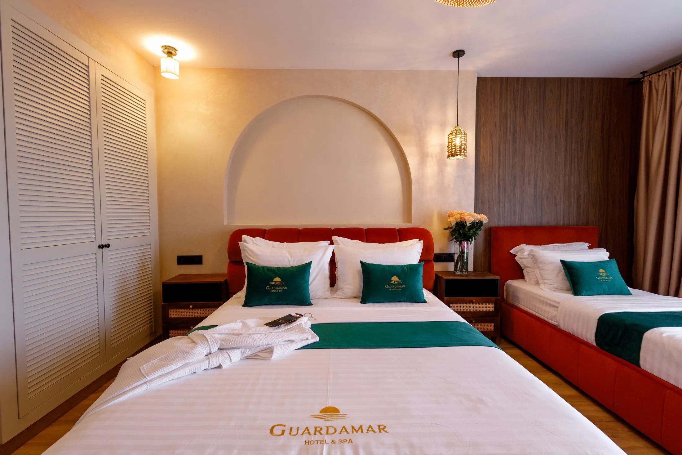 Habitación de hotel con dos camas, un ventanal arqueado grande y vistas al cielo nocturno.