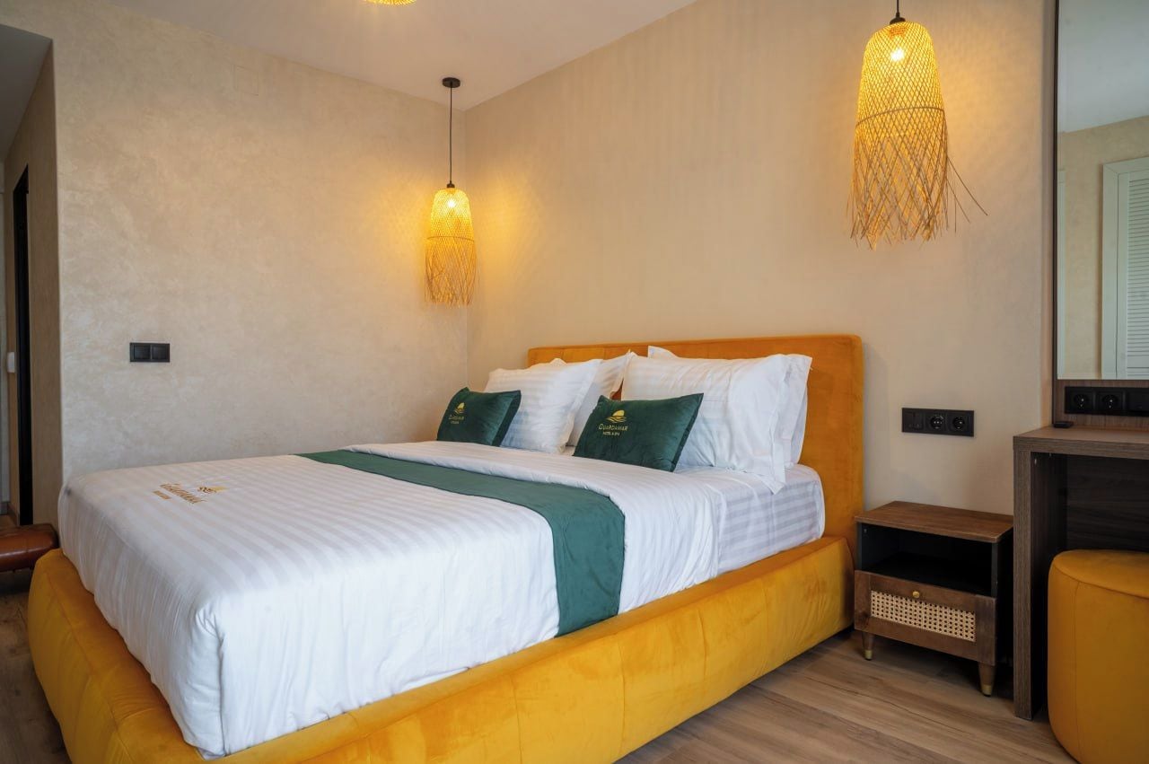 A hotel room with a bed, bedside tables, and a mirror.