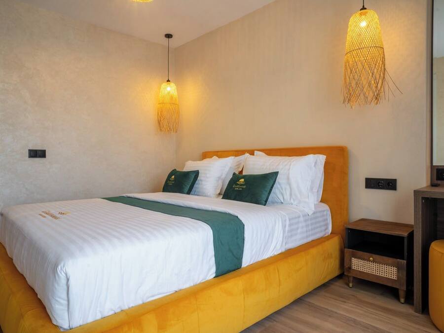 A hotel room with a bed, bedside tables, and a mirror.
