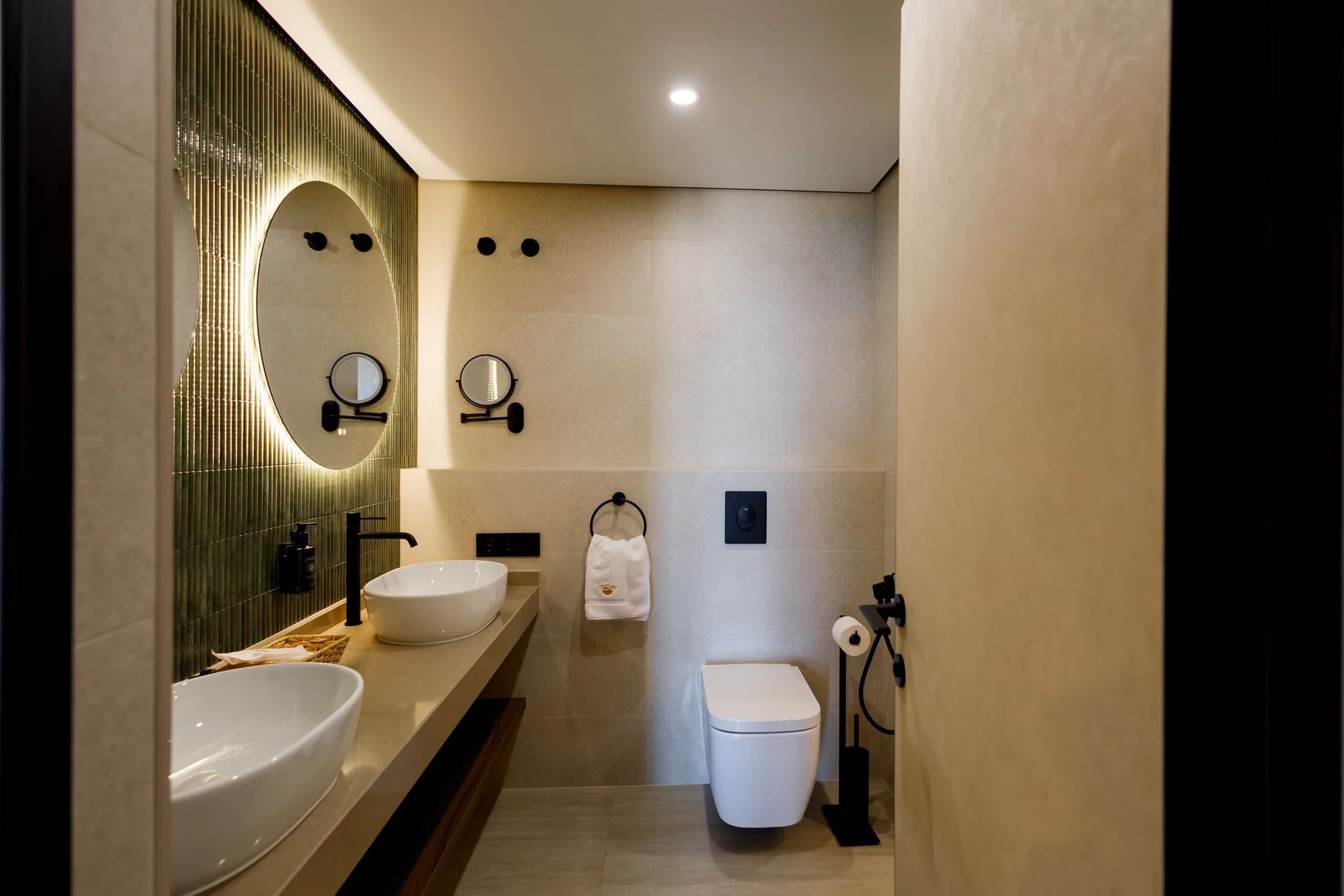 Un baño moderno con dos lavamanos, un inodoro y un espejo de diseño exclusivo.