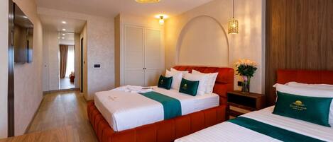 A hotel room with two beds, a wooden floor, a red upholstered headboard, and a wall-mounted light fixture.