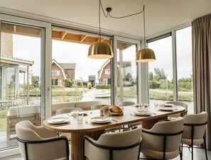 A dining area with a large table, chairs, and pendant lighting. - Exclusive 6-person Water Villa in Heeg (Heeg)