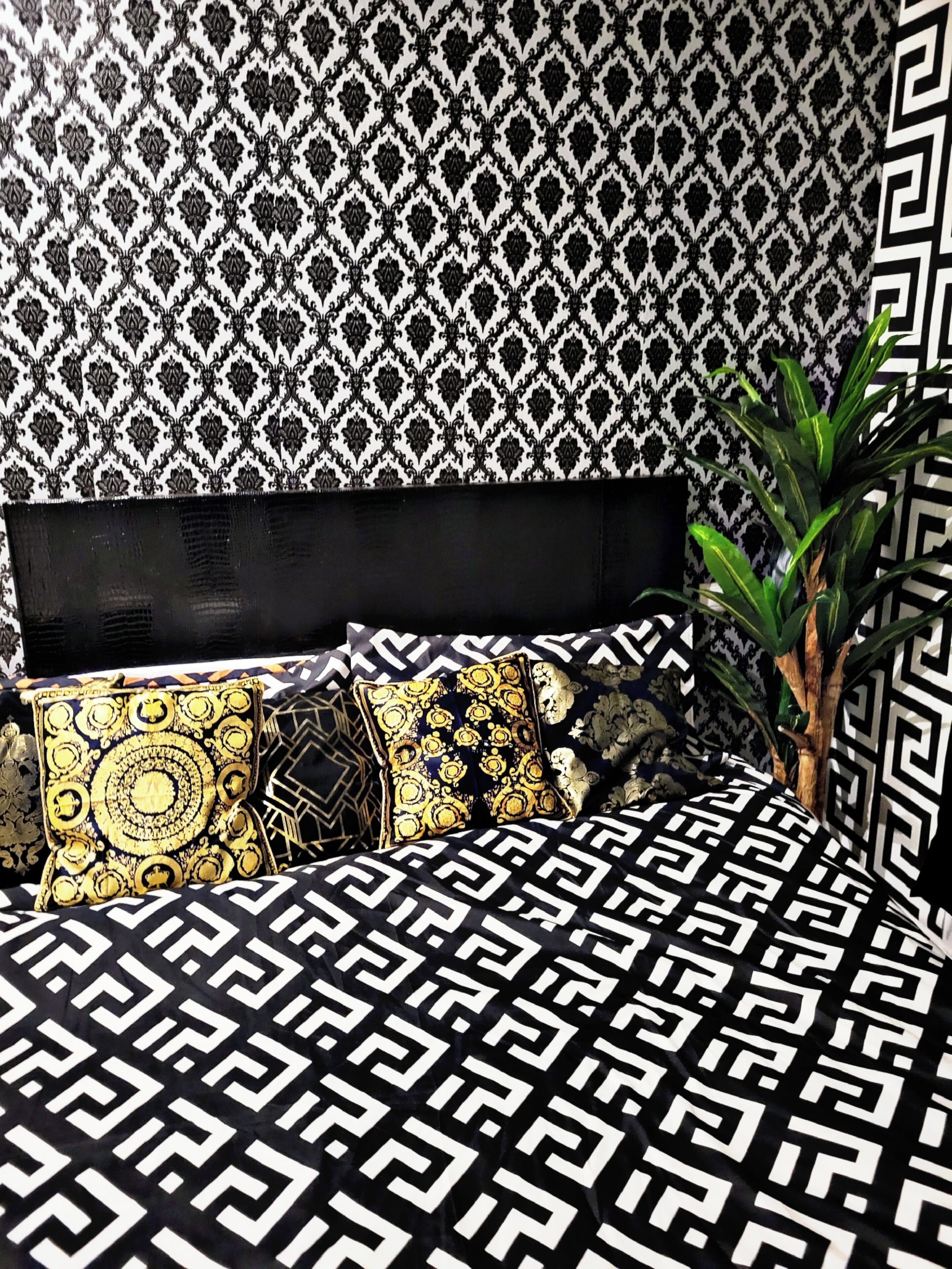 Un lit avec une couvre-lit à motifs noir et blanc, une tête de lit noire et des coussins décoratifs.