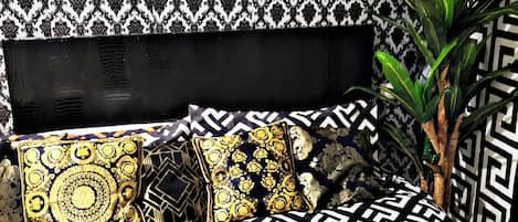 Un lit avec une couvre-lit à motifs noir et blanc, une tête de lit noire et des coussins décoratifs.