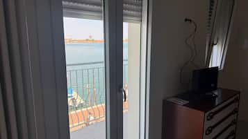 Ein Zimmer mit Blick auf ein Gewässer, ein Balkon mit Geländer und eine Holzkommode mit Schubladen.