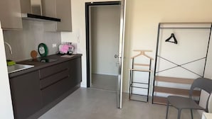 Un espacio habitable compacto con kitchenette, una cama, un armario y una zona de estar.