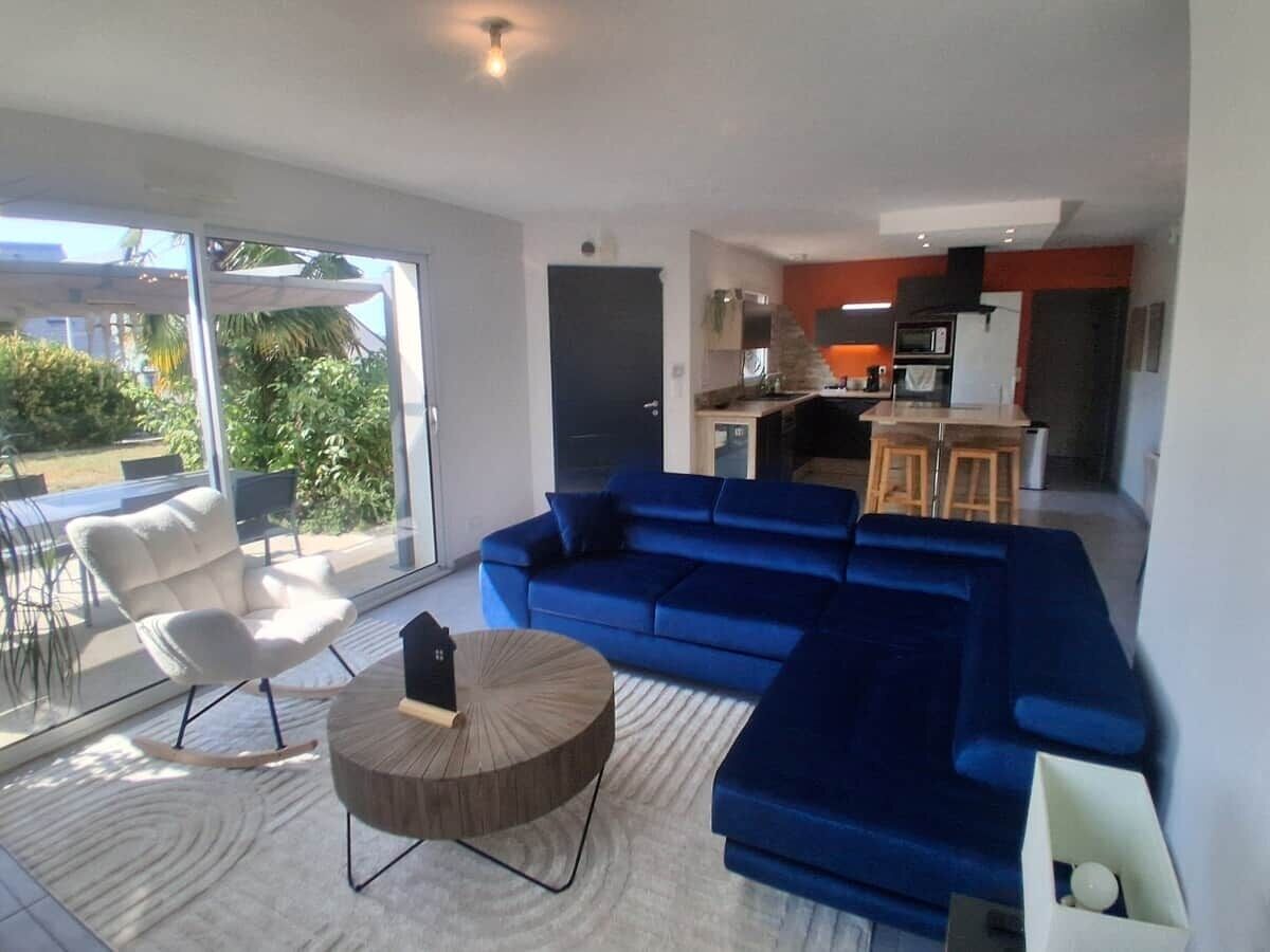 Ein modernes Wohnzimmer mit einem blauen Modulsessel, einem weißen Sessel und einem runden Couchtisch.