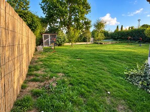 Ein gepflegter Rasen mit Holzzaun, einer kleinen Spielanlage und einem Fußballtor.