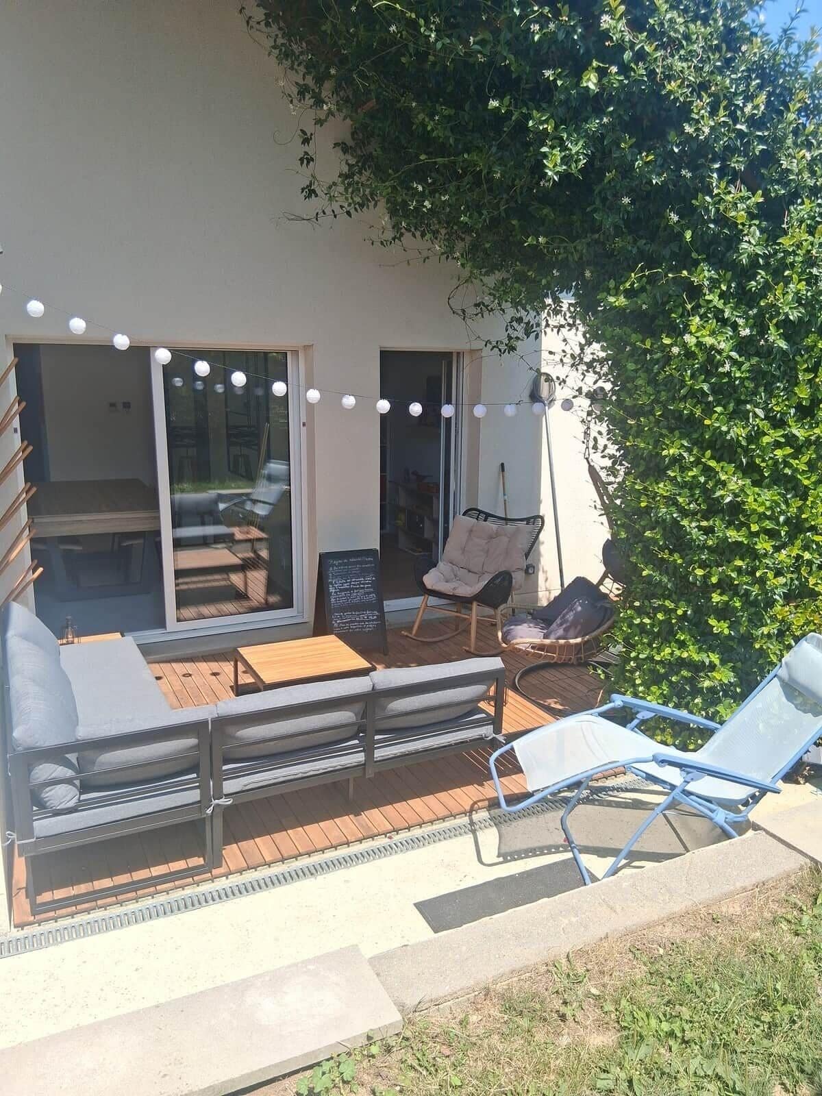Eine Terrass mit Holzdeck, einem Esstisch und zwei Loungestühlen.