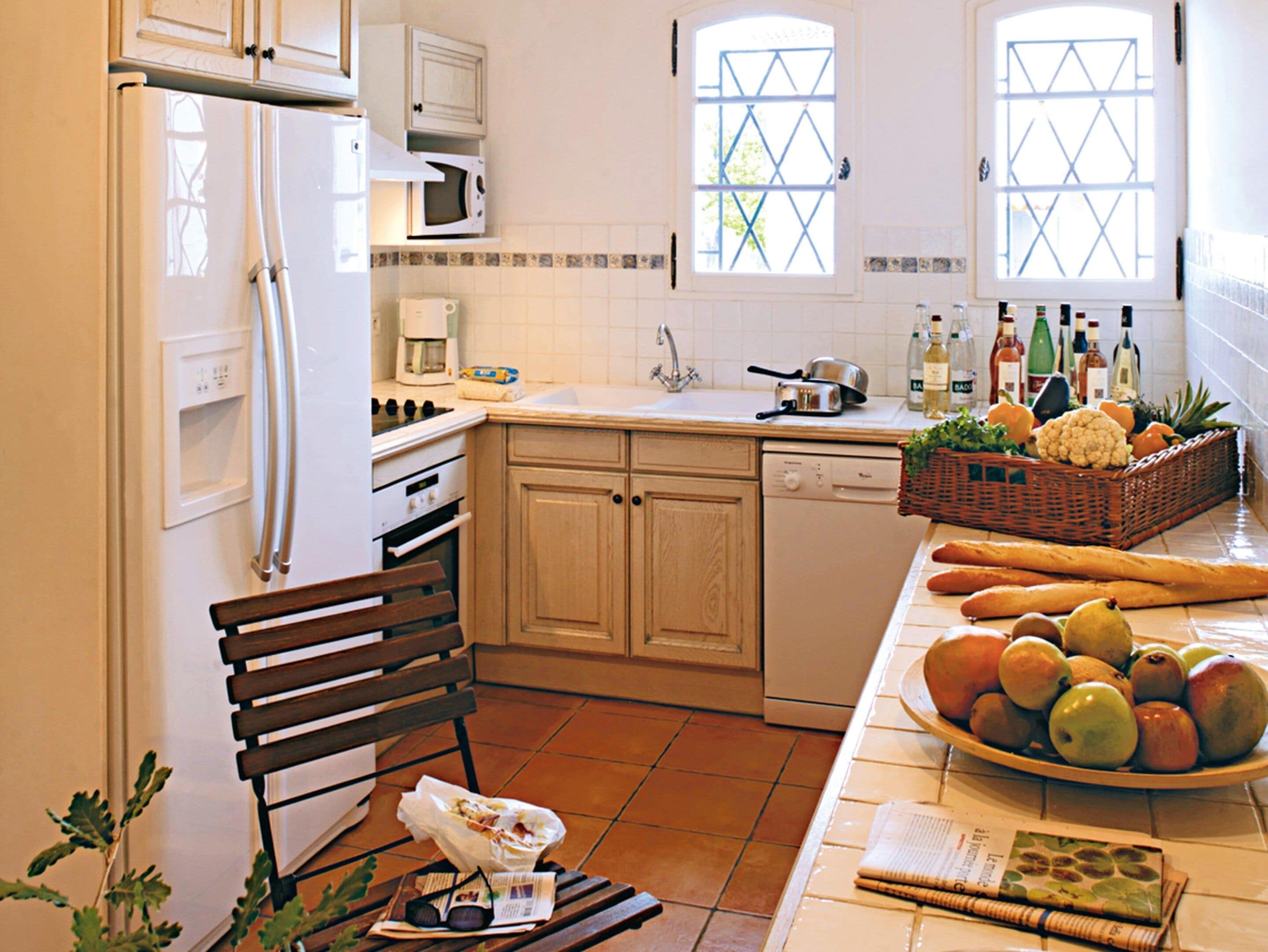 Una cocina equipada con refrigerador, microondas, estufa y lavavajillas. Se aprecia una ventana con vistas a la vegetación.