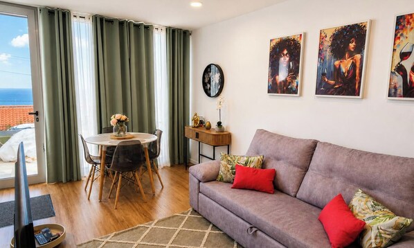 Een woonkamer met een bank, een eettafel en kunst aan de muur.