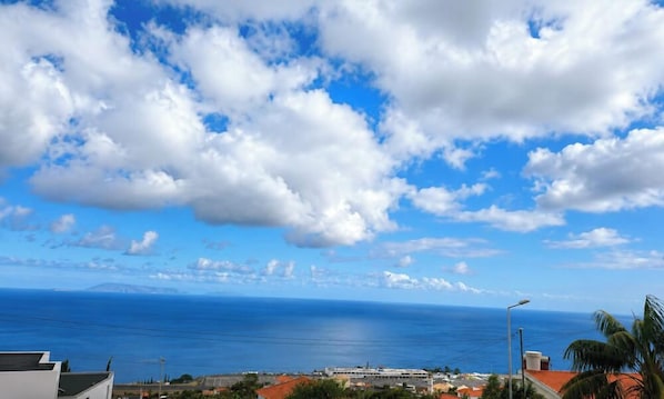 Eine Küstenansicht bei blauem Himmel, mit einem Gewässer und einer fernen Insel.